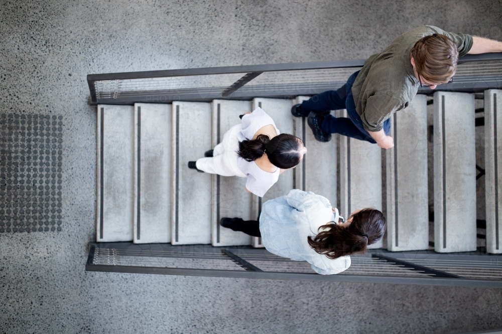 Top view of three small business workers standing on concrete stairs in an industrial office - Australian Stock Image