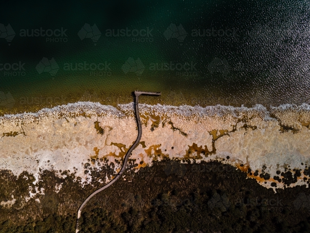 top view shot of a beach walkway with bushes, trees and waves on a sunny day - Australian Stock Image