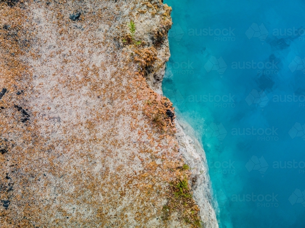 top view shot of a blue water meeting with a brown and white rock formation - Australian Stock Image