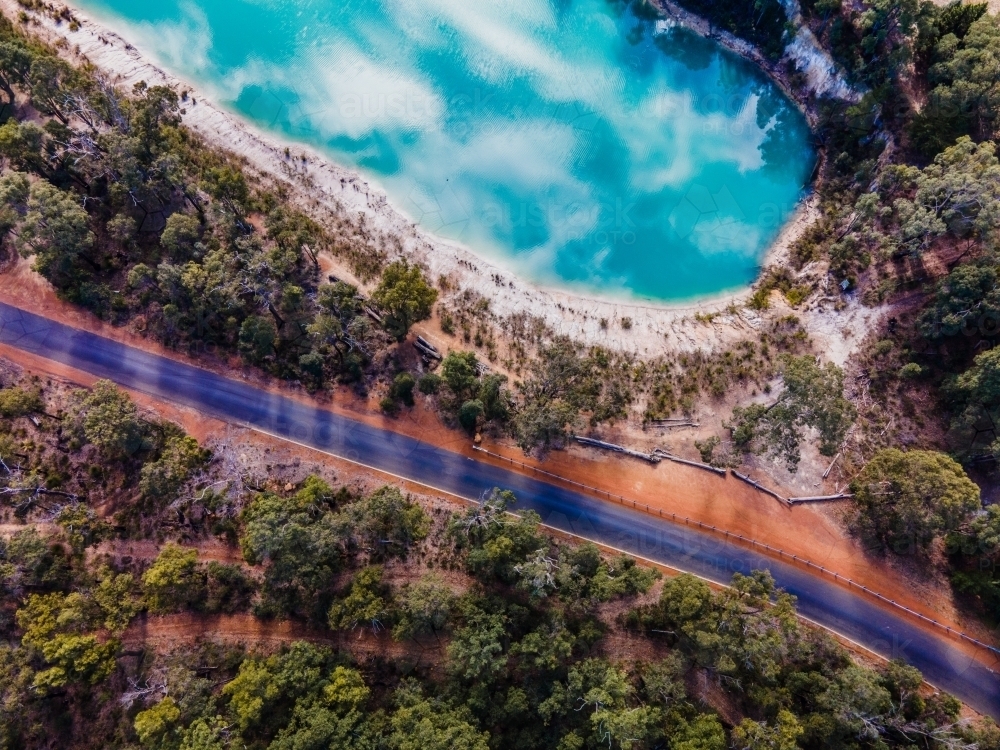 top view shot of blue lake with a sky reflection, with green trees and a road - Australian Stock Image