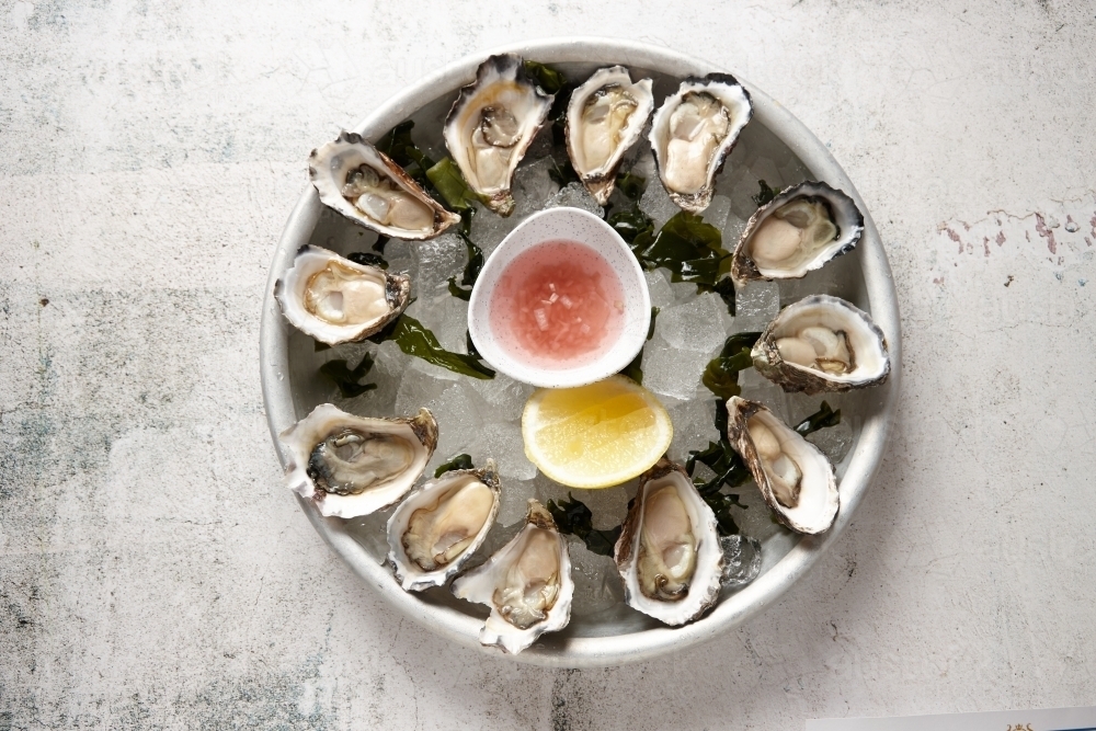 top view shot of fresh oyster seafood platter on top of ice cubs with bowls of sauce - Australian Stock Image