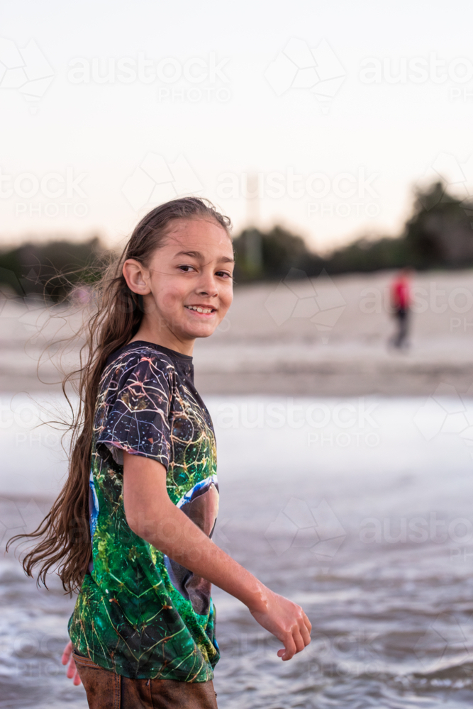 Torres Strait Islander boy wading in ocean water at dusk - Australian Stock Image
