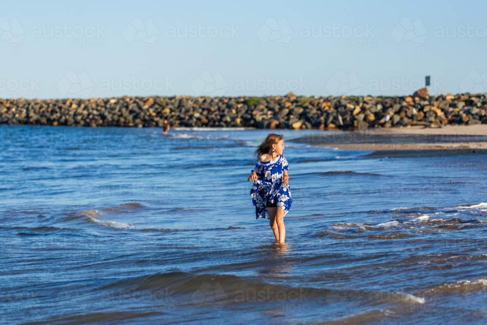 Torres Strait Islander child playing in water at beach on windy day - Australian Stock Image