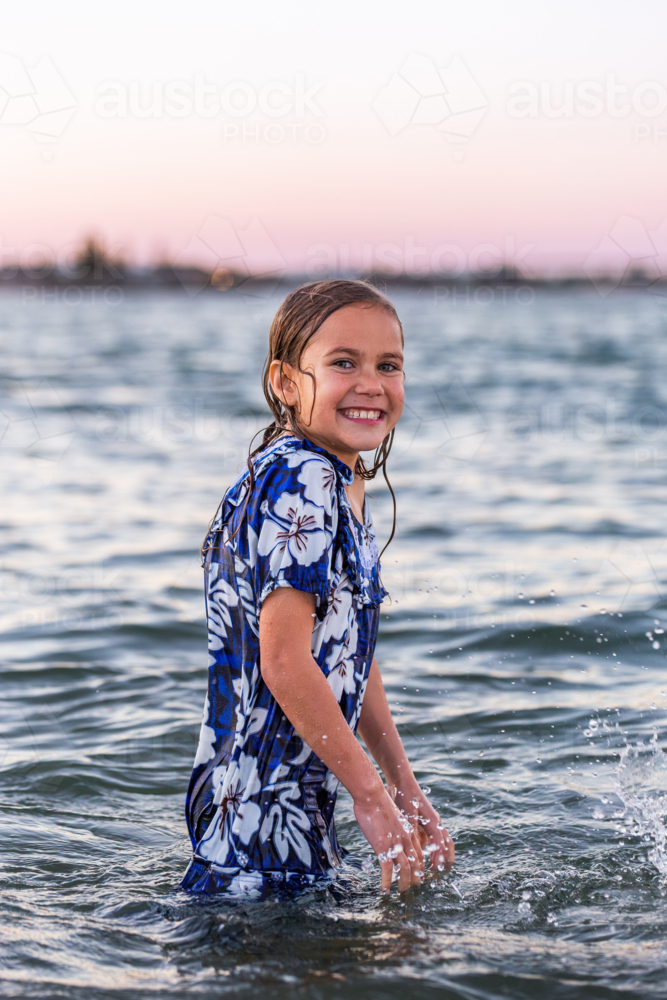 Image of Torres Strait Islander child splashing in ocean water at dusk ...