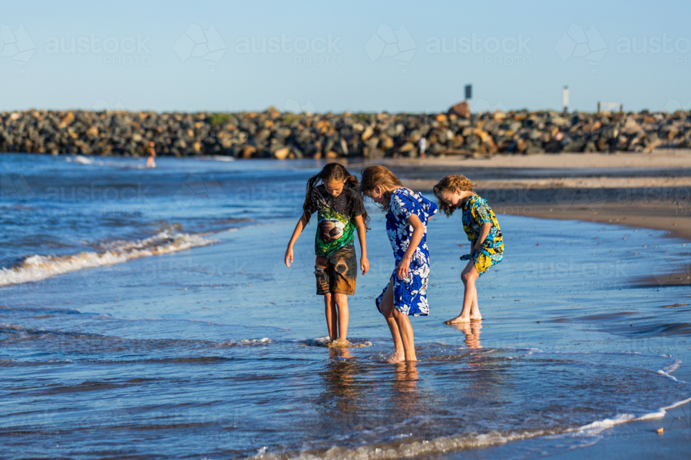 Torres Strait Islander children playing together at beach on windy day - Australian Stock Image