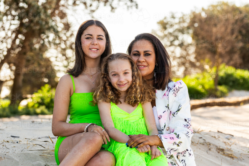Torres Strait Islander family with mum and two daughters together at beach - Australian Stock Image