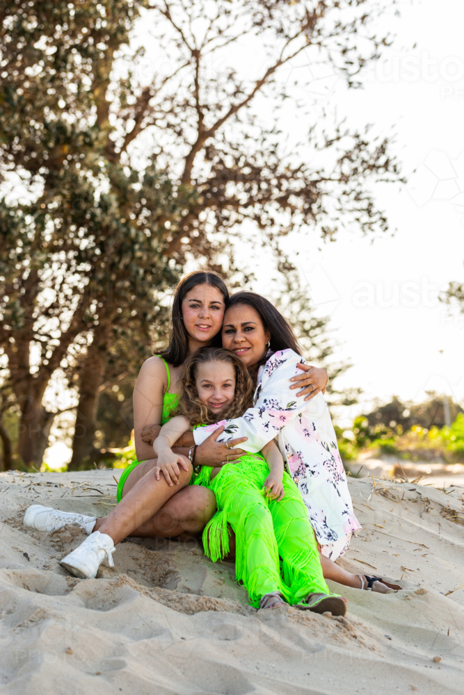 Torres Strait Islander family with mum and two daughters together at beach - Australian Stock Image