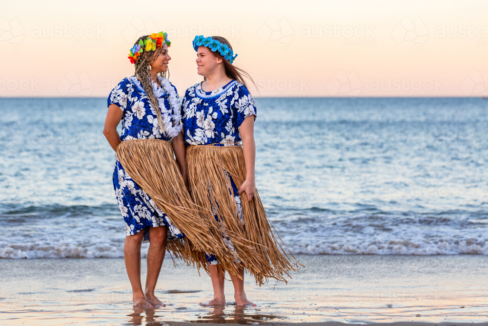 Torres Strait Islander mum with teenaged daughter looking at each other by the ocean at dusk - Australian Stock Image