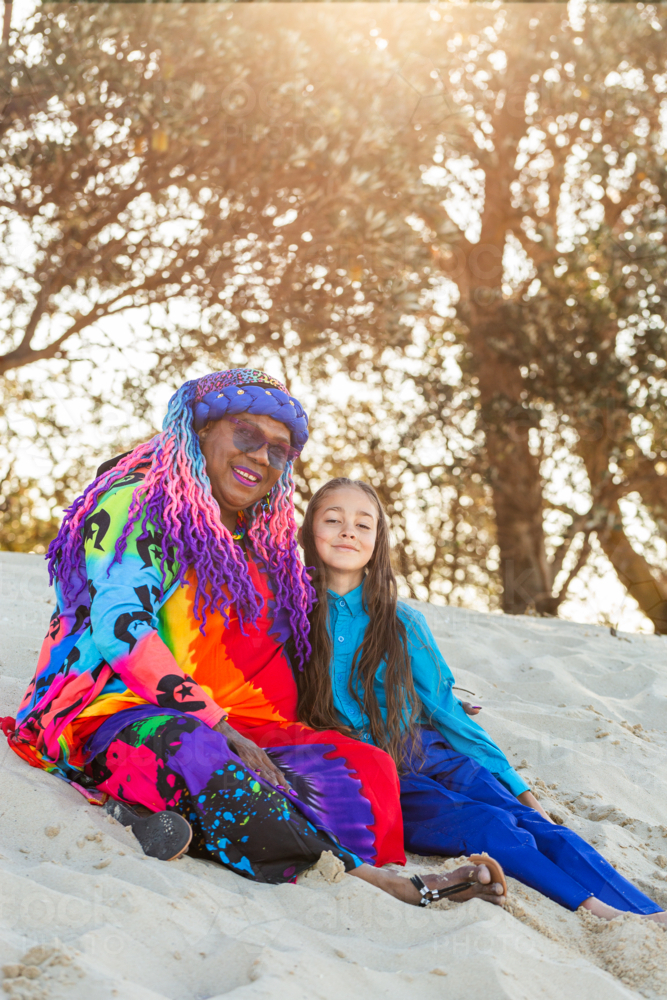 Torres Strait Islander nine year old boy with long hair sitting beside grandmother on the beach - Australian Stock Image