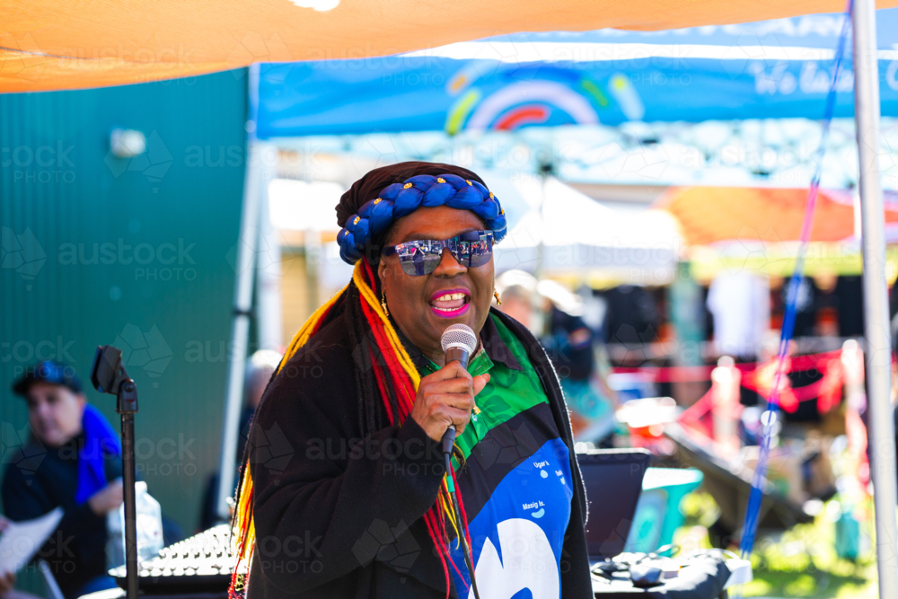 Torres Strait Islander woman singing at DJ booth at NAIDOC cultural event - Australian Stock Image