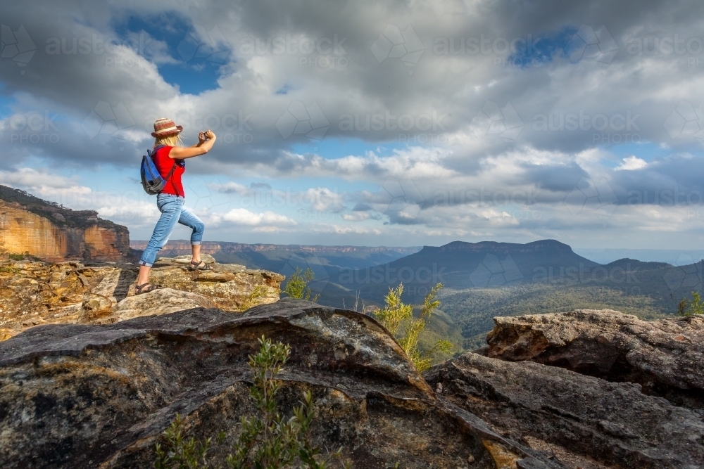 Tourist taking photos from cliff tops of stunning panoramic Blue Mountain vistas - Australian Stock Image