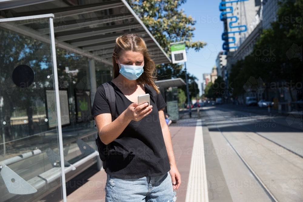Tourist Wearing Face Mask Waiting for the Tram - Australian Stock Image