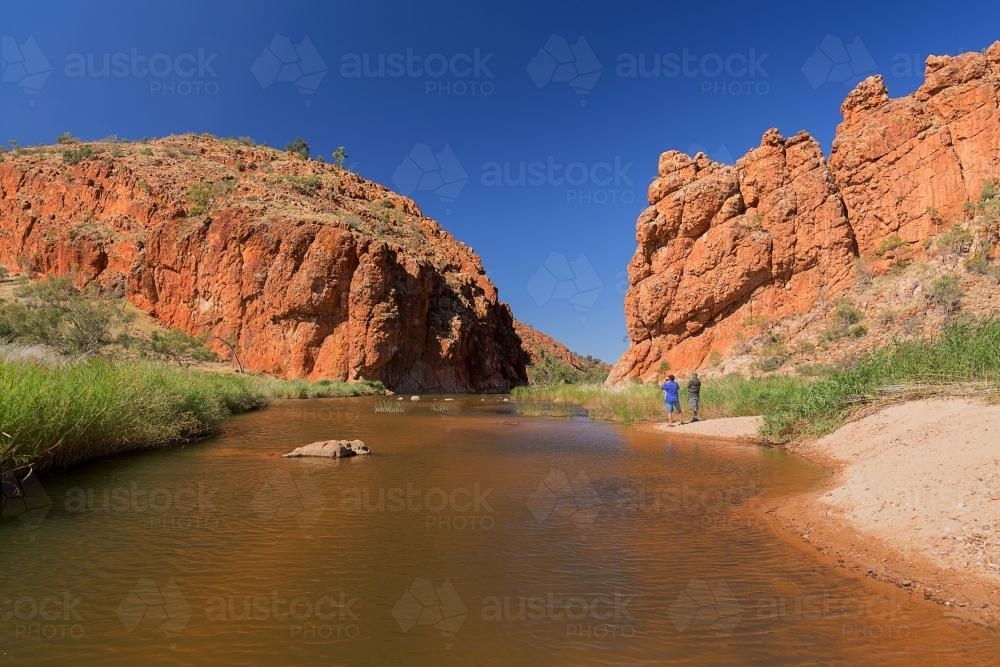 Tourists beside a river coming from a gorge - Australian Stock Image