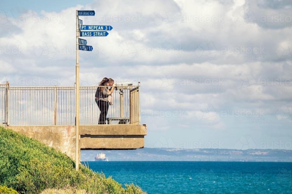 Tourists looking out to sea through a telescope - Australian Stock Image