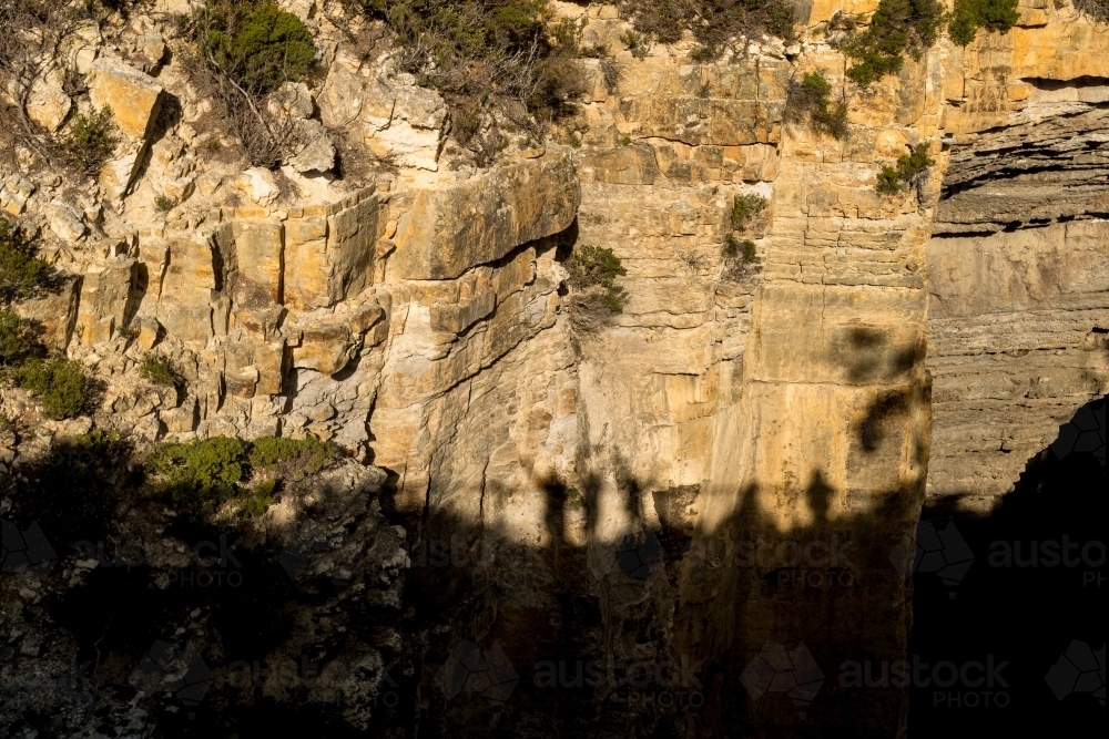 tourists making shadows on a cliff face - Australian Stock Image