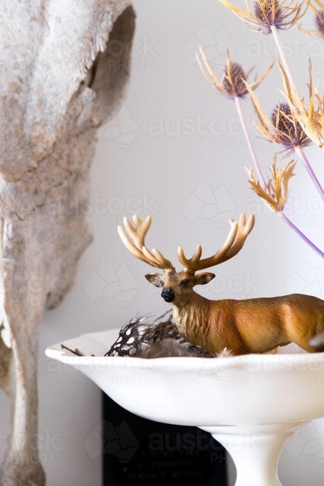 Toy deer in a bowl with feathers and dried seed heads - Australian Stock Image