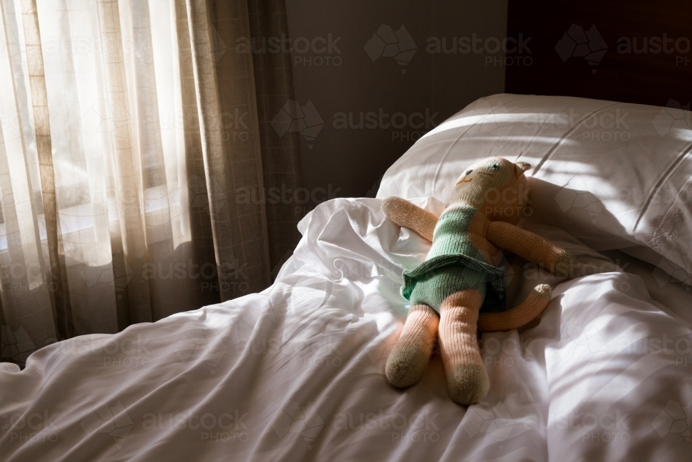 Toy on an unmade bed in the morning light - Australian Stock Image