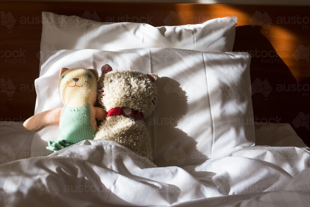 Toys on an unmade bed in the morning light - Australian Stock Image