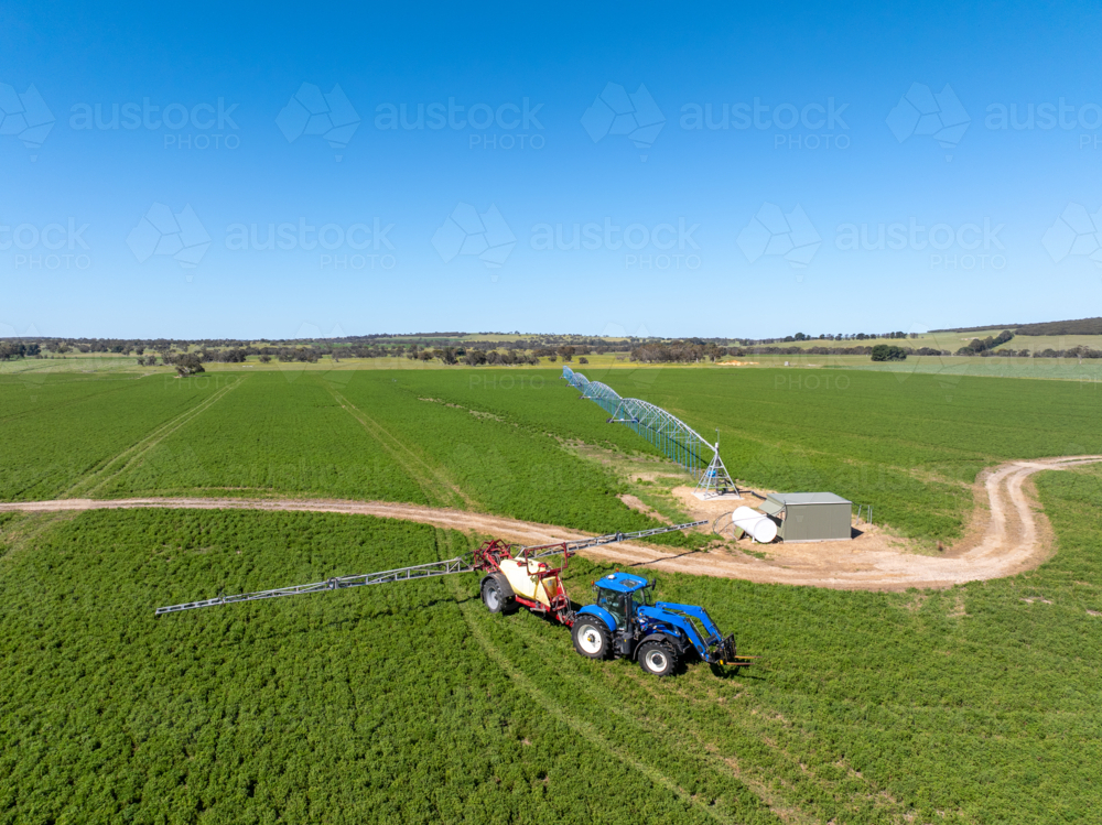 Tractor and Boomspray next to a Centre Pivot Irrigator in a paddock of Lucerne : Austockphoto Tractor and Boomspray next to a Centre Pivot Irrigator in a paddock of Lucerne - Australian Stock Image