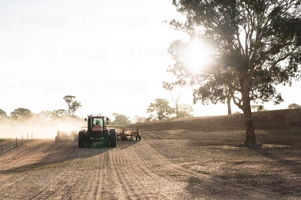 Tractor cultivating a farm paddock making dust on a sunny day - Australian Stock Image