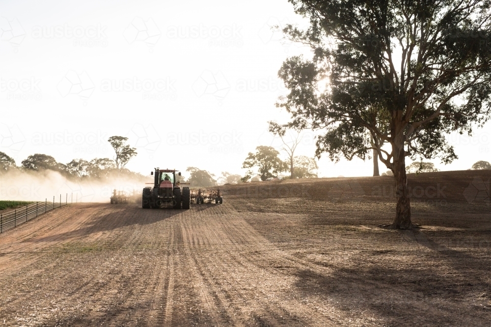 Tractor cultivating the field on a sunny day dust rising - Australian Stock Image