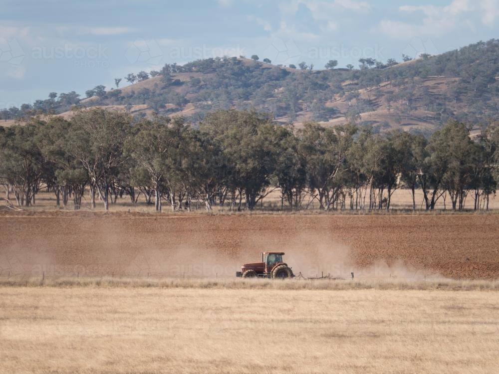 Tractor ploughing a paddock with dust swirling - Australian Stock Image