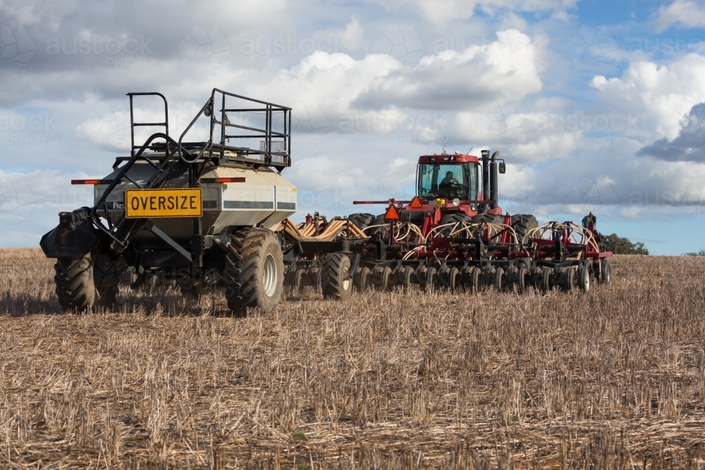Tractor ploughing soil with cultivator smashing  clods in the  beds - Australian Stock Image