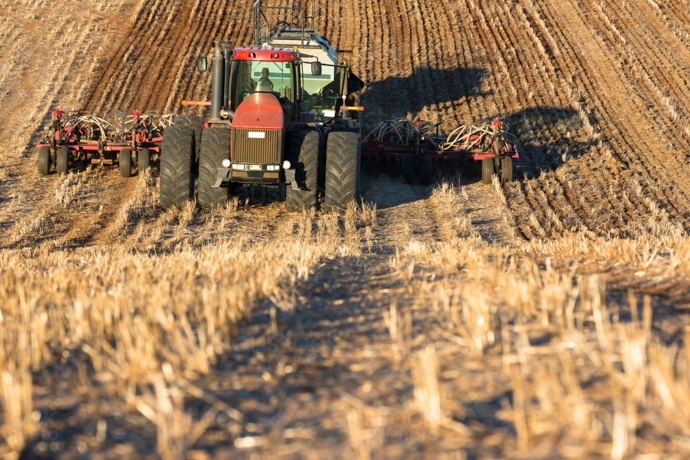 Tractor ploughing soil with cultivator smashing clods in the paddock - Australian Stock Image
