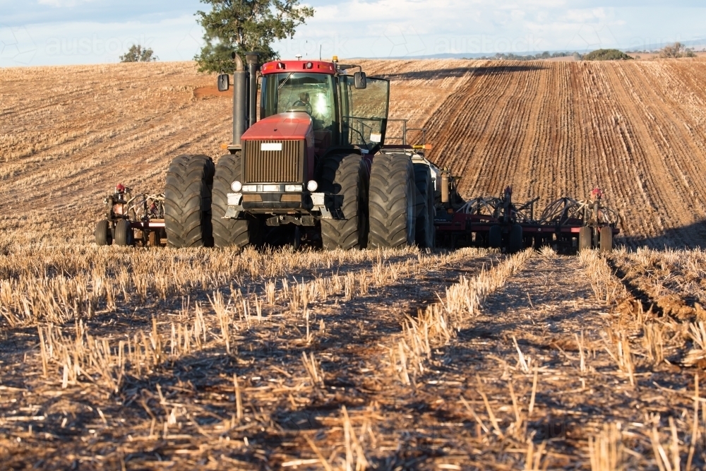 Tractor ploughing soil with cultivator smashing clods in the paddock - Australian Stock Image
