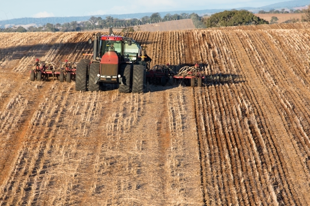 Tractor ploughing soil with cultivator smashing dirt clods in the beds - Australian Stock Image