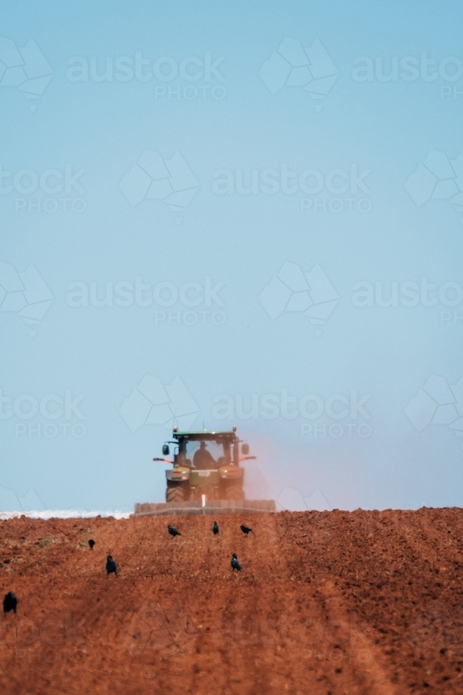 Tractor plowing red dirt for cropping. - Australian Stock Image
