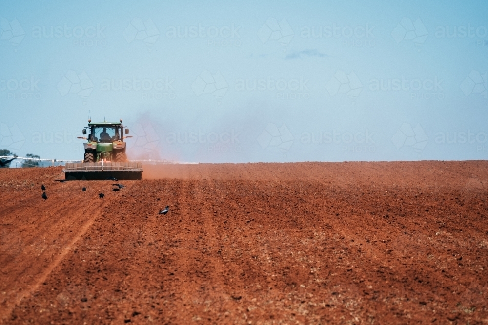 Tractor plows red dirt ready for cropping. - Australian Stock Image