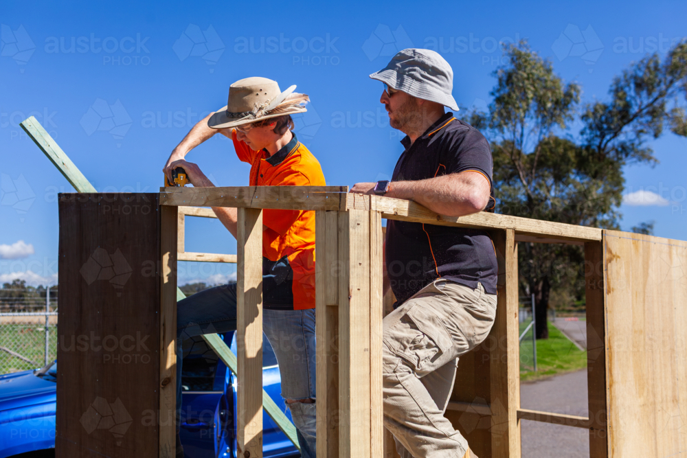 Trade apprentice and teacher working on construction of ticket booth - Australian Stock Image