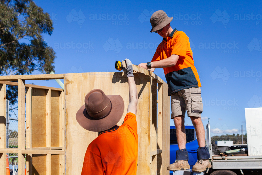 Trade apprentices learning hands on while constructing ticket booth in bright Australian sunlight - Australian Stock Image