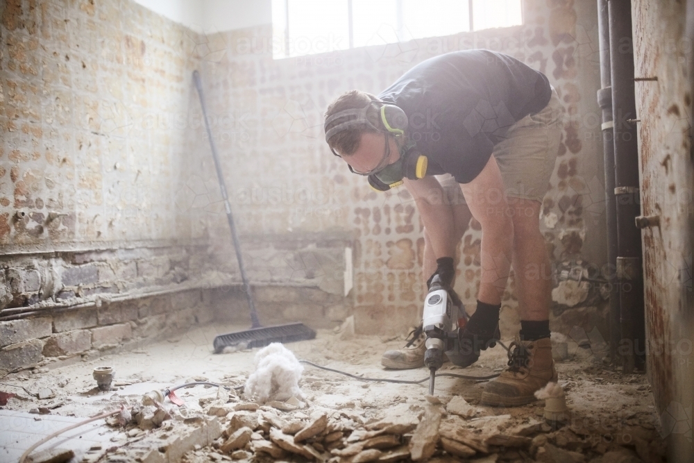 Tradesman jackhammering a floor in a home renovation - Australian Stock Image