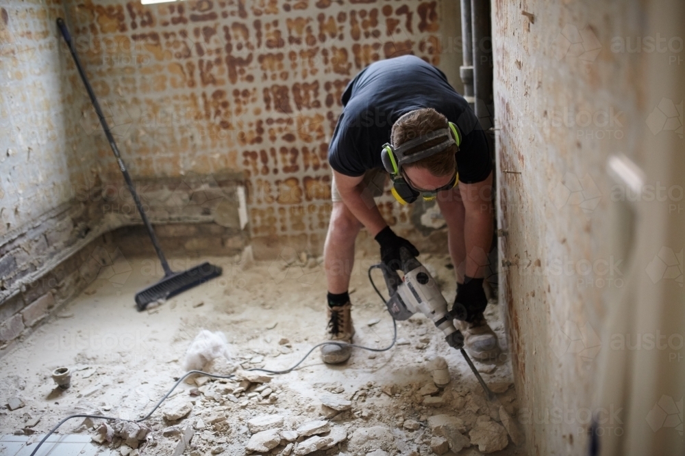 Tradesman jackhammering a floor in a renovation - Australian Stock Image