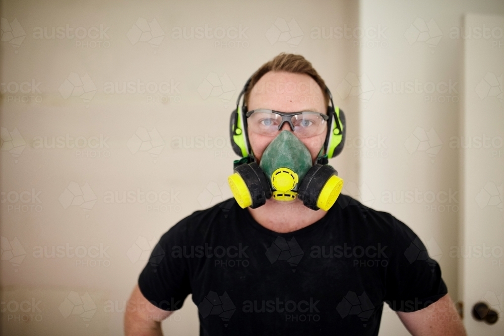 Tradesman standing in a room in a construction zone wearing protective equipment - Australian Stock Image