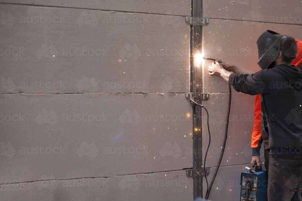 Tradesman welding fencing in a home environment - Australian Stock Image