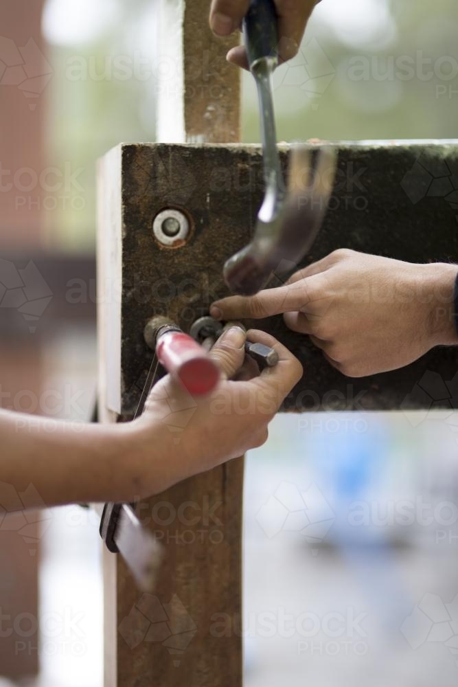 Tradesmen attaching a washer to secure a bolt to a wooden beam. - Australian Stock Image