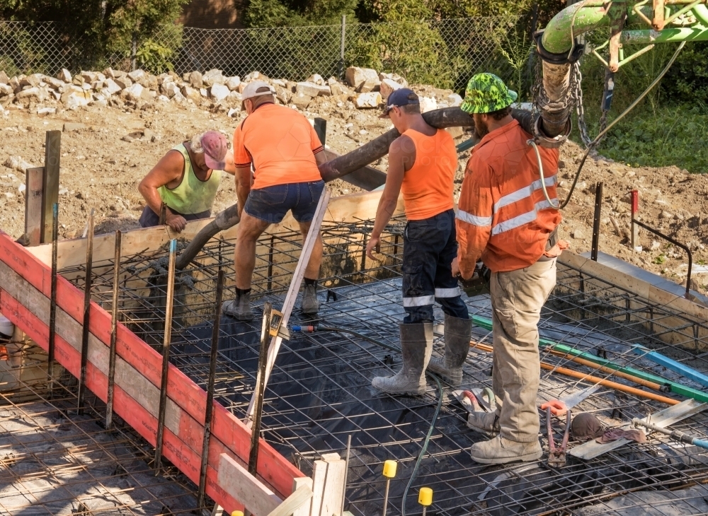 Tradesmen using concrete pump to pour footings on building site - Australian Stock Image