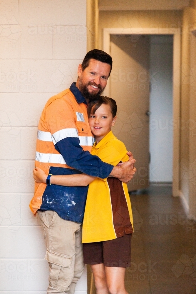 Tradie dad and Aussie school girl hug before going to work in the morning - Australian Stock Image