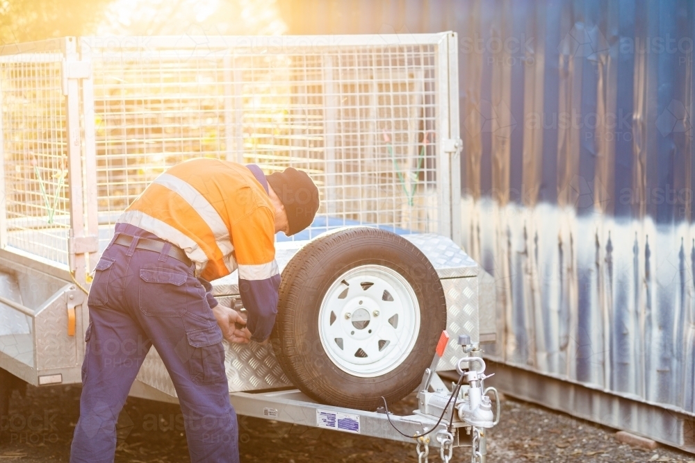 Tradie in golden light opening up lock box on trailer - Australian Stock Image