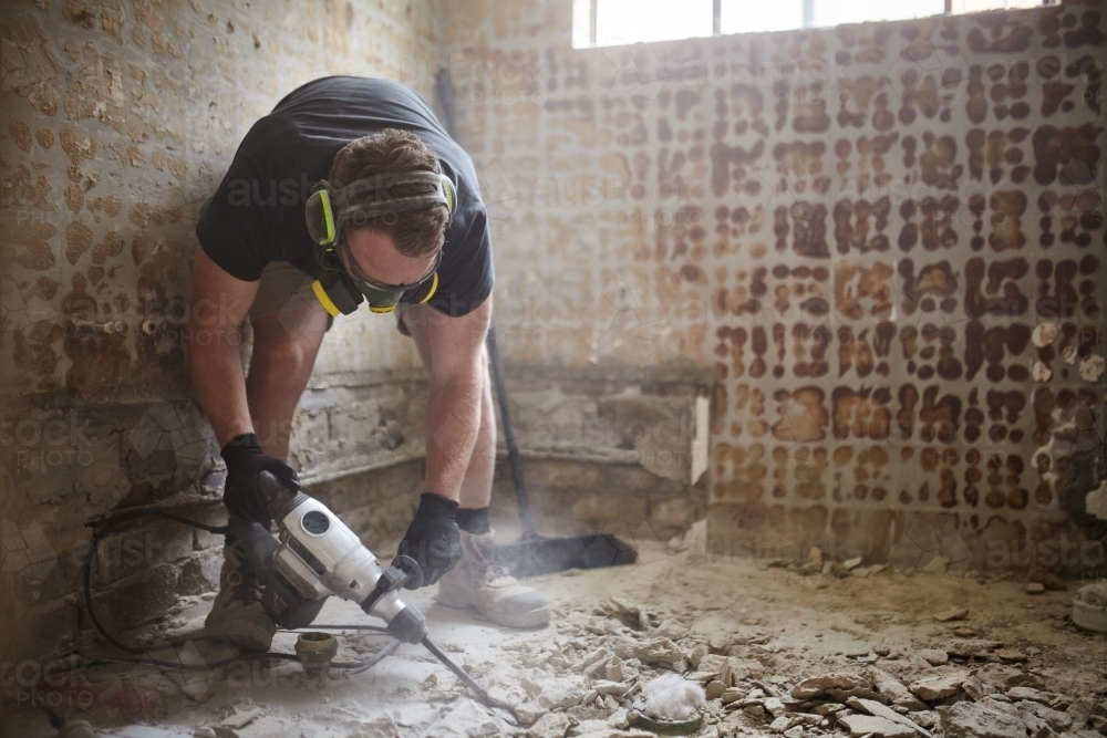 Tradie jackhammering a floor in a renovation site - Australian Stock Image