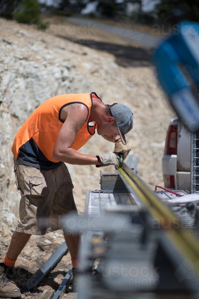 Tradie measuring metal frame on construction site - Australian Stock Image