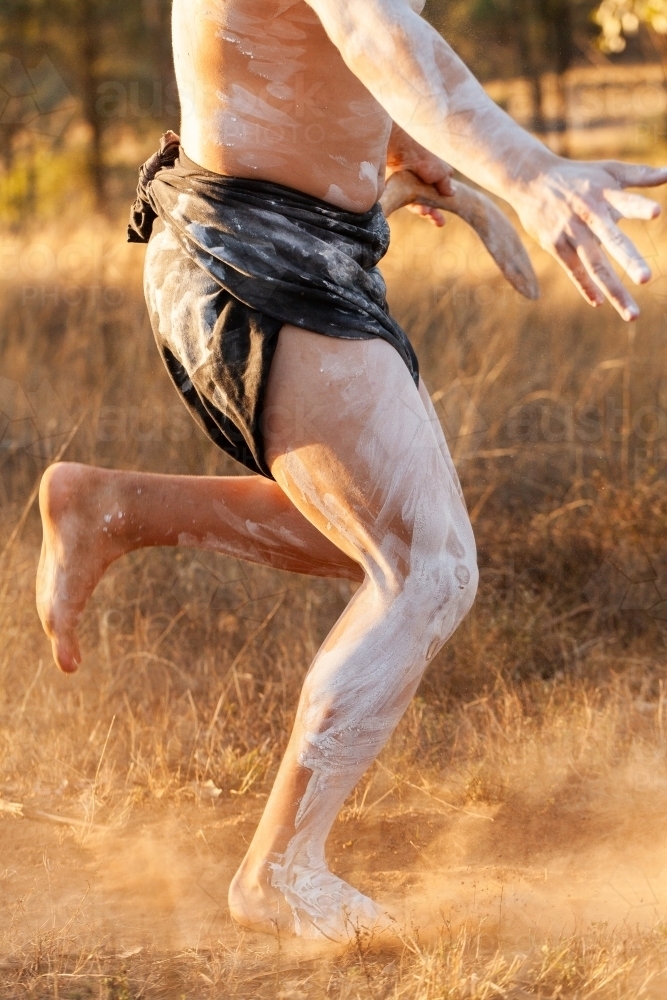 Traditional aboriginal dance on country kicking up dust and wearing body paint - Australian Stock Image