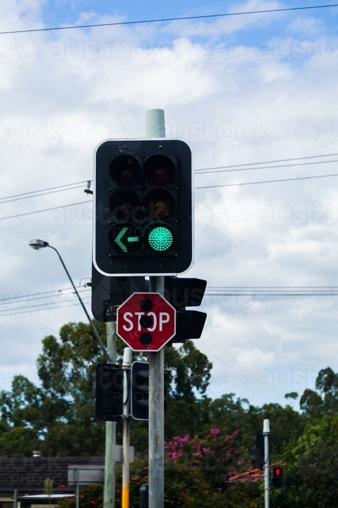 traffic light with green arrow and stop sign at city intersection - Australian Stock Image
