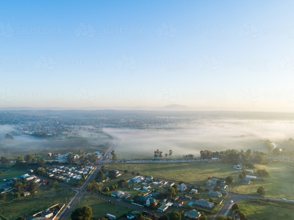 Traffic lights intersection of highway through Singleton with paddock and mist covered landscape at - Australian Stock Image