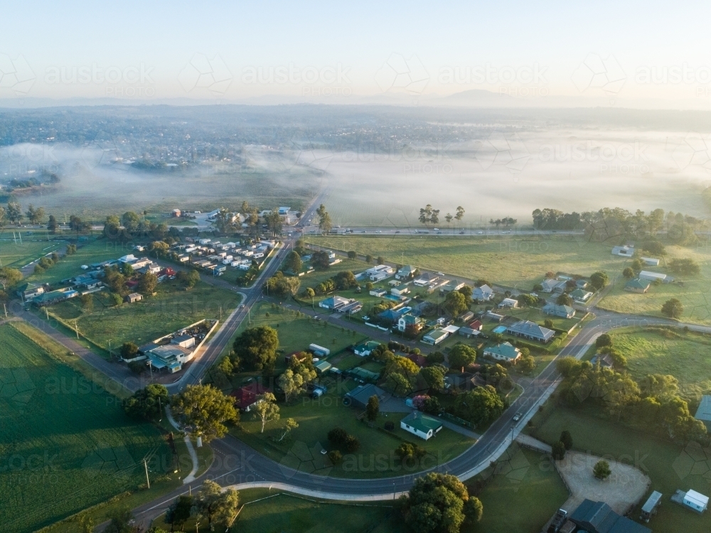 Traffic lights intersection of highway through Singleton with paddock and mist covered landscape at - Australian Stock Image