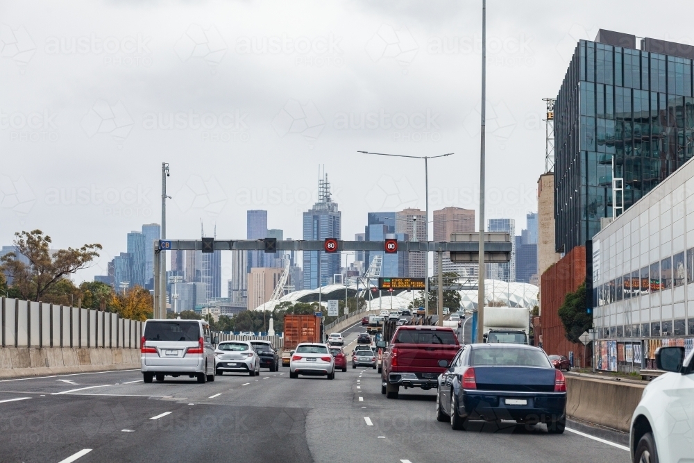 Traffic on multi lane city road to Melbourne CBD with variable speed limit signs reading 80 - Australian Stock Image