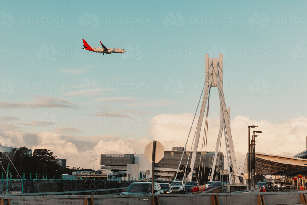 Traffic on road at Sydney Domestic Airport with plane flying overhead - Australian Stock Image